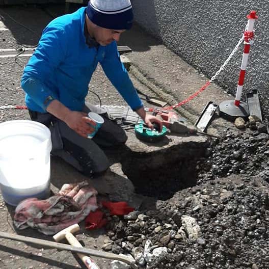 Man looking in hole in street for leak